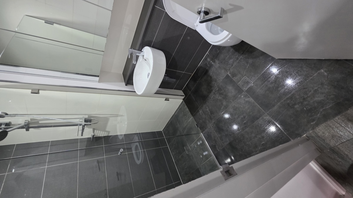 Dark marble bathroom with glass shower screen cleaned to inspection standard